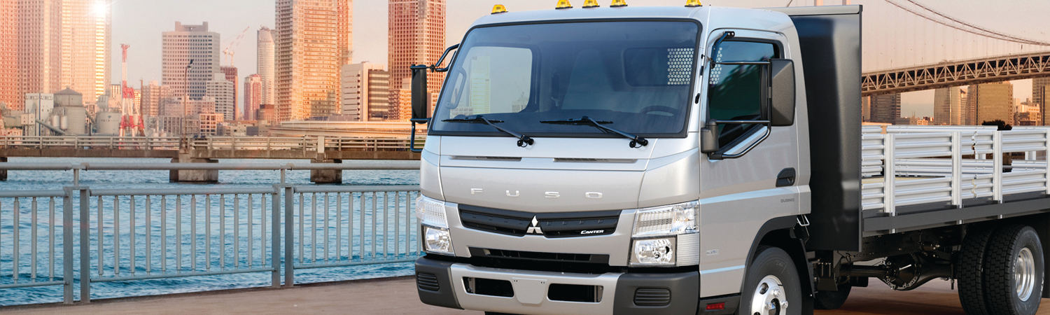 2017 Fuso Canter truck parked next to a scenic waterfront.