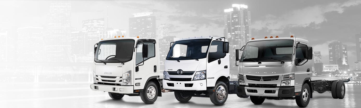 Isuzu, Hino, and Mitsubishi Trucks with background of urban city