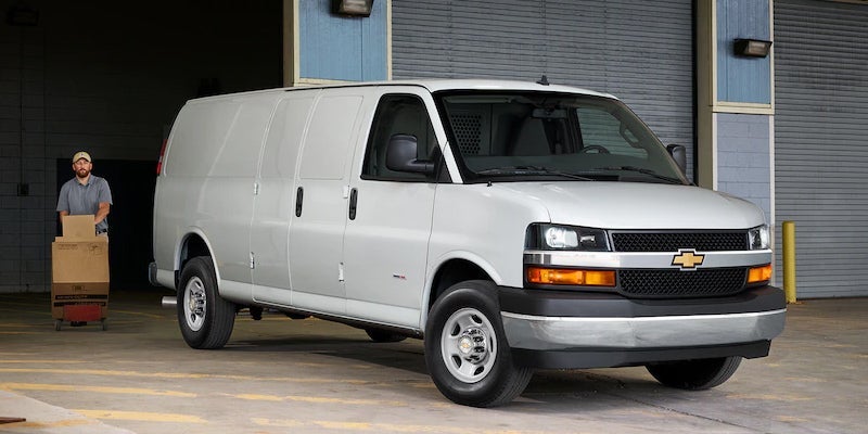 White Chevrolet Express cargo van shown from a front three-quarter angle near a warehouse loading area