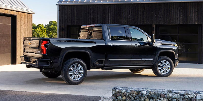Black Chevrolet Silverado pickup truck parked outside a modern building, shown in side profile with a clean exterior setting.